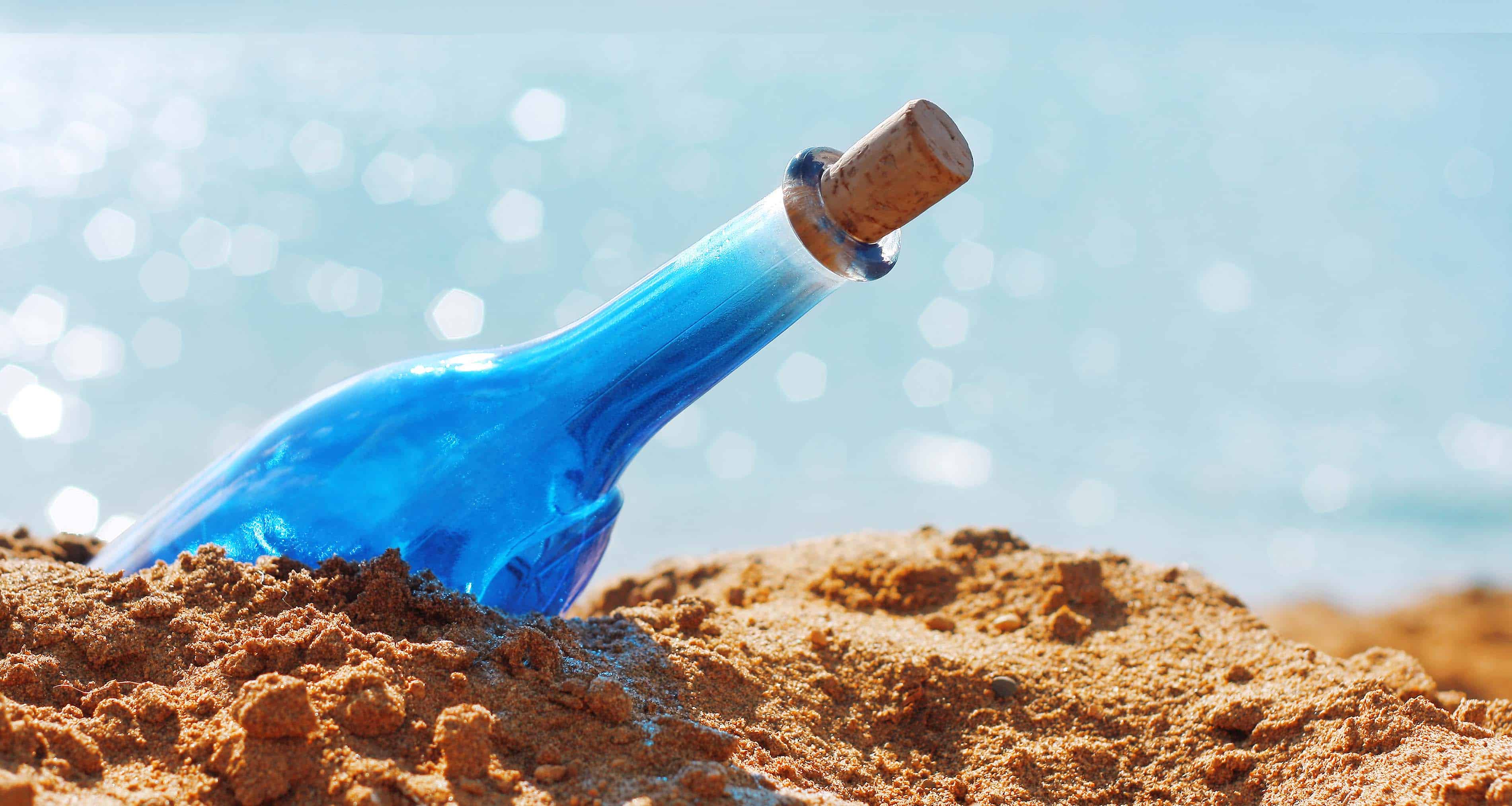 Blue glass bottle in sand and airy clouds like genie - Ancestral-Energy